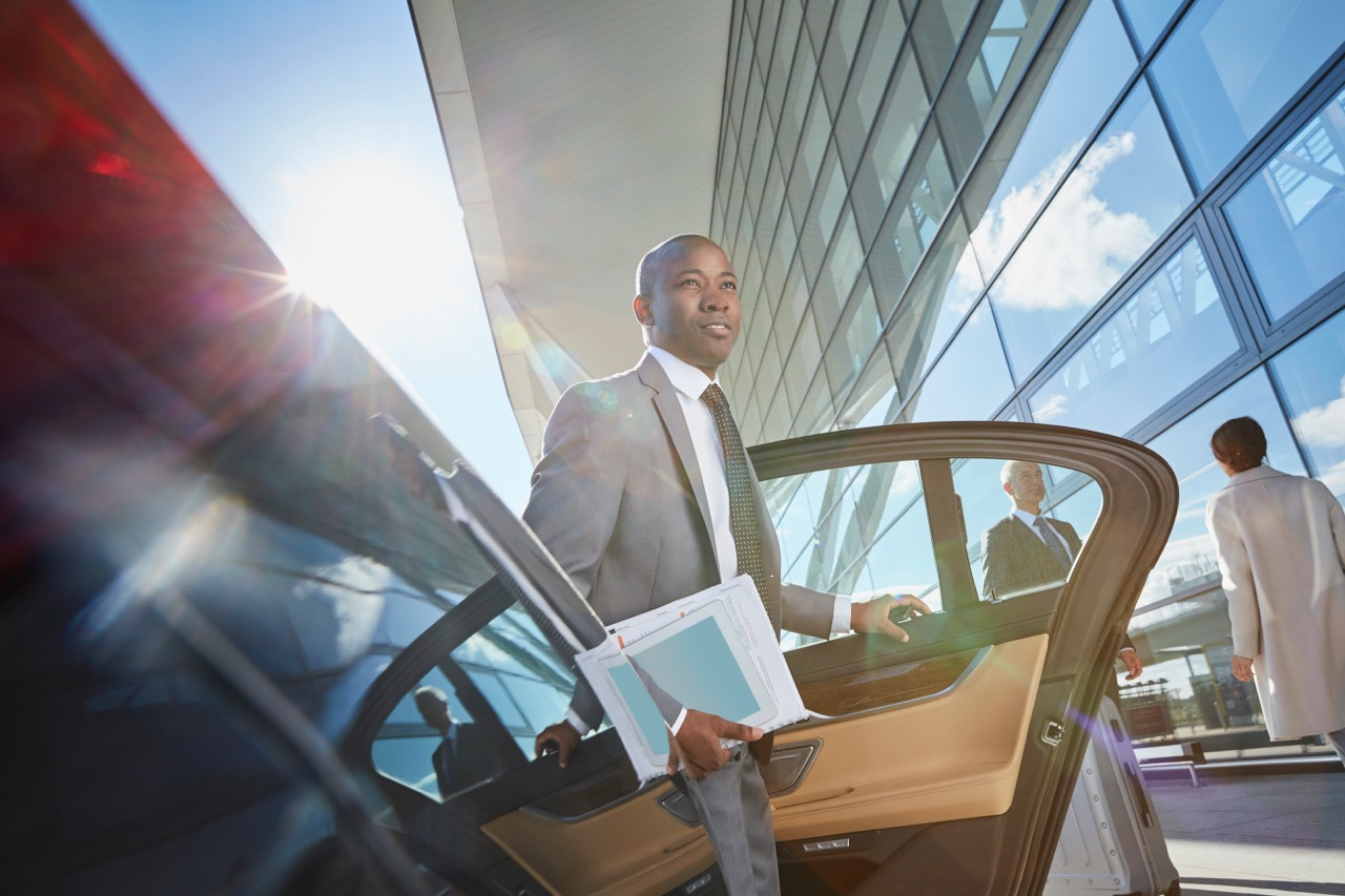 Business traveller arriving at airport and entering a chauffeur vehicle